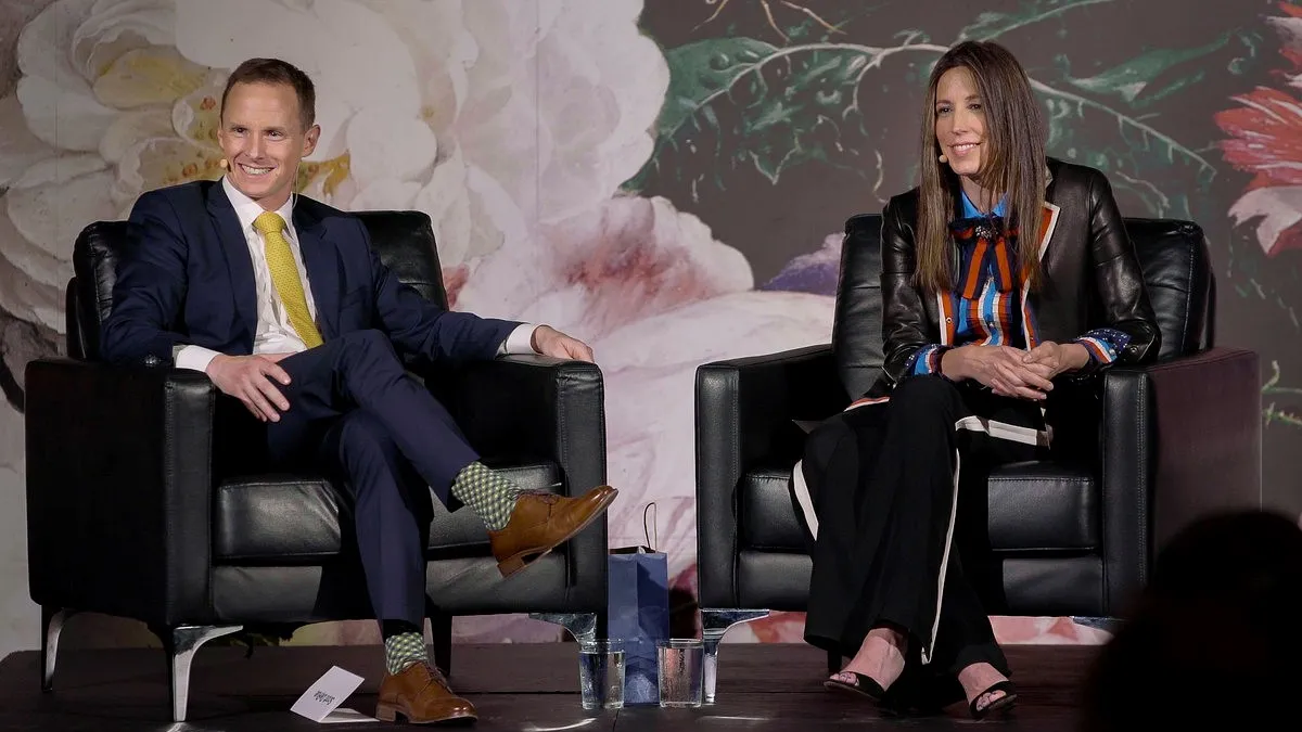 A still from a video. Two people, Scott DeRue and Jenny Just, sitting in chairs and facing an audience.